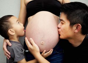 son and husband kissing pregnant belly twins photoshoot home