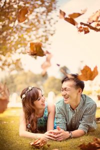 laughing couple lying on lawn with golden brown leaves