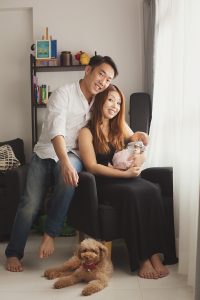 proud parents with infant newborn and pet poodle home shoot