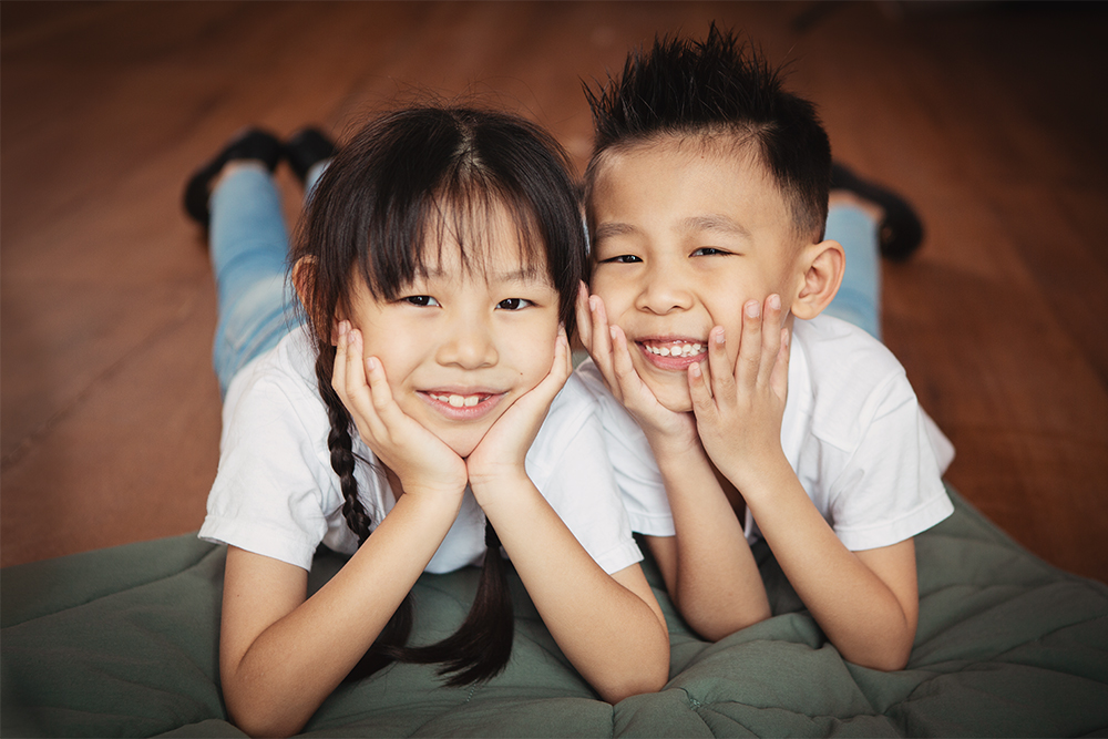 Happy sibling photoshoot lying on rustic wooden floor