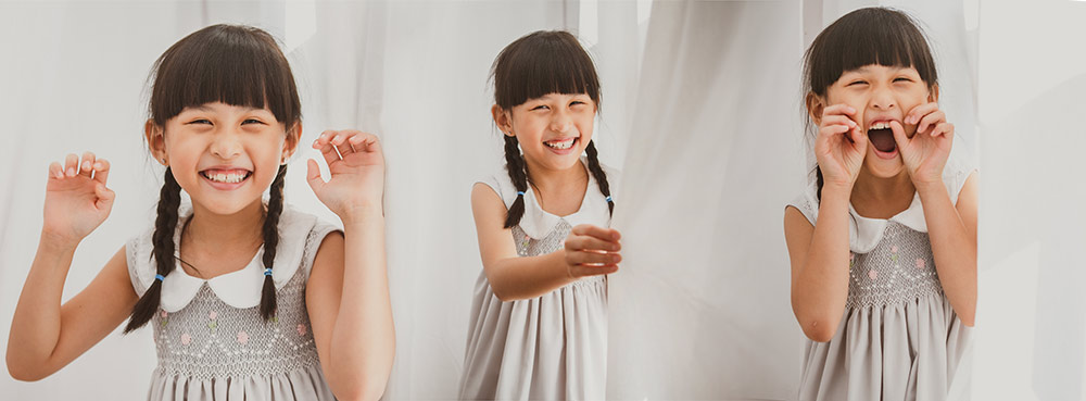 Little girl having fun laughing and playing among white curtain