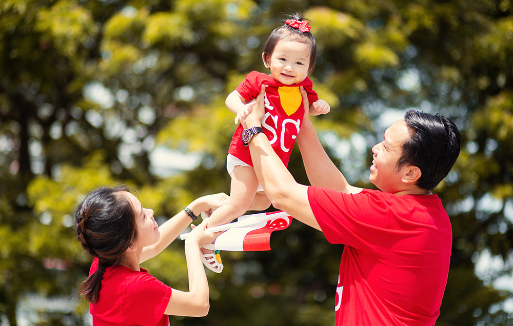 Parents playing with one year old baby in greenery