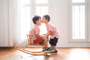 brothers on rocking horse by window