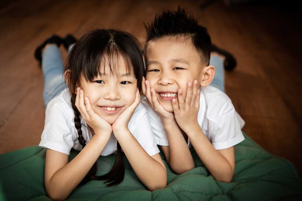 Sibling photoshoot lying on wooden floor
