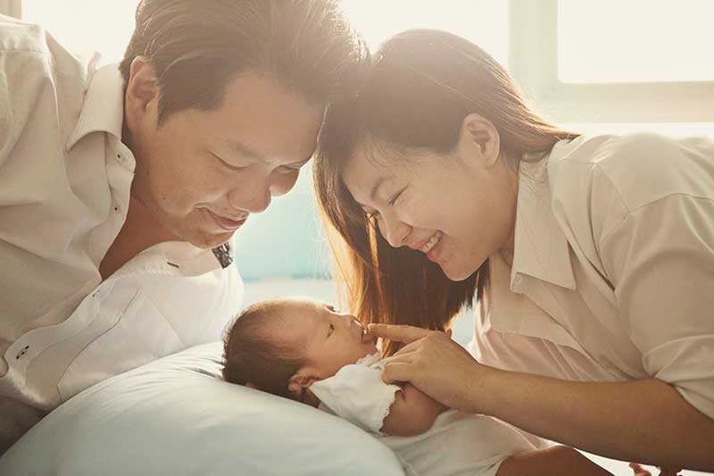 Family with newborn smiling golden sunlight