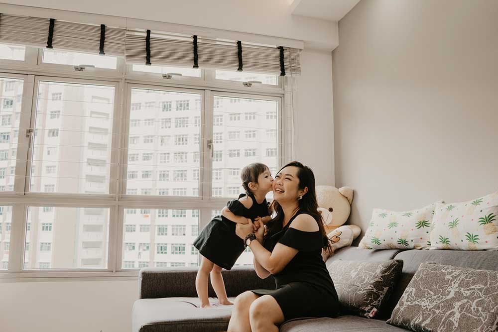 daughter kissing mummy at home living room 