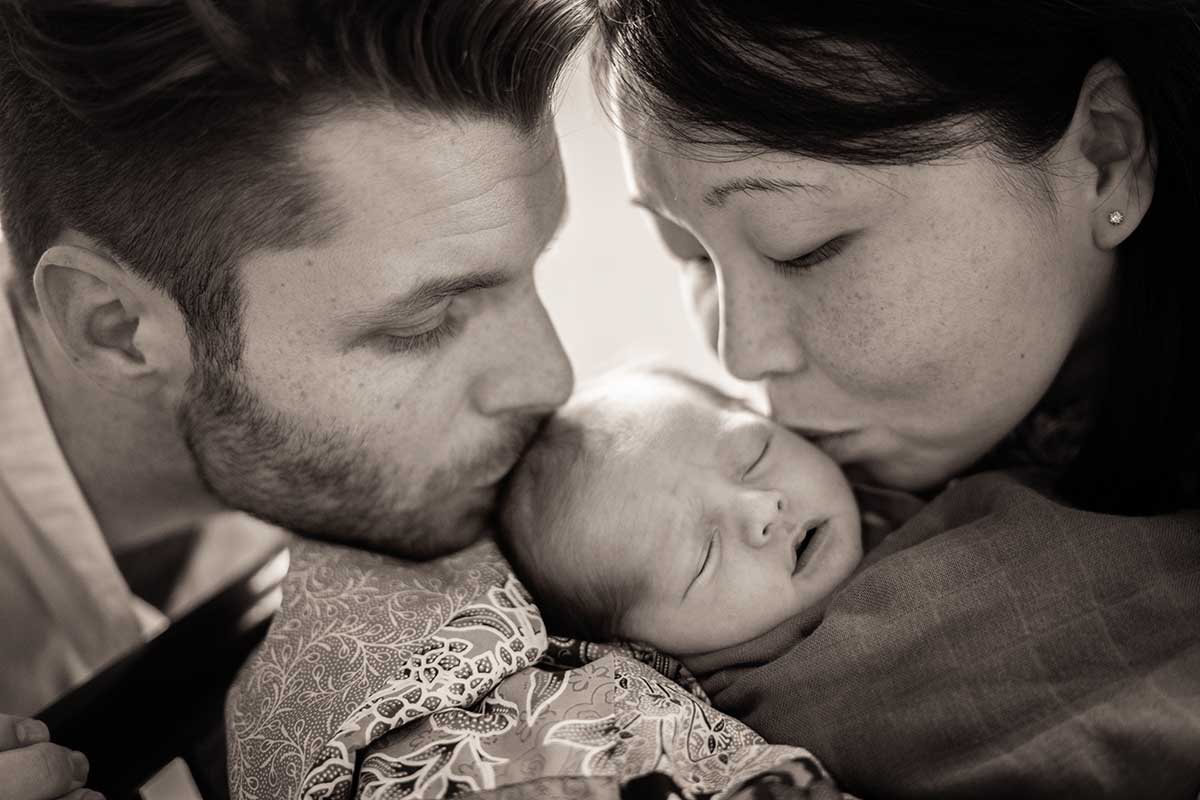 parents kissing 5 days old newborn baby