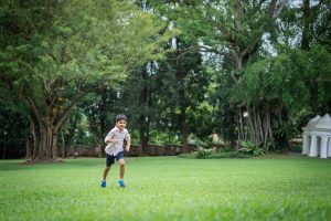 boy running on fort canning park lawn