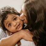 mother kissing one year old baby boy