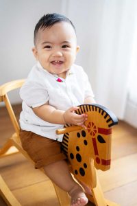 laughing one year old on rocking horse