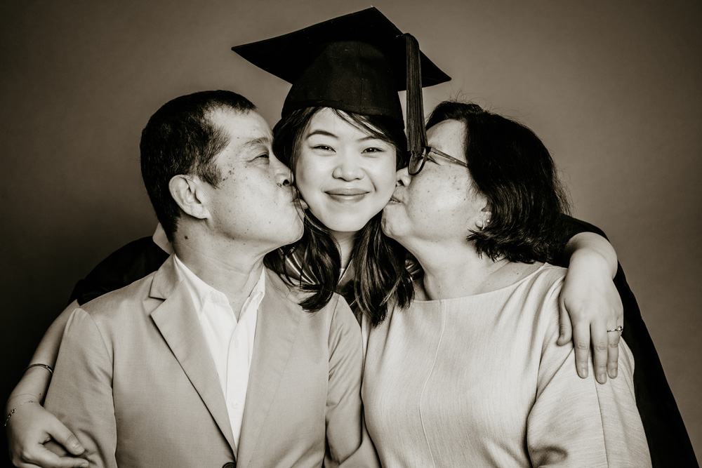 parents kissing graduate photoshoot