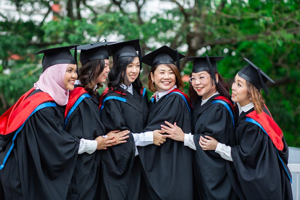 A group of ladies in graduation gowns and posing for a picture 