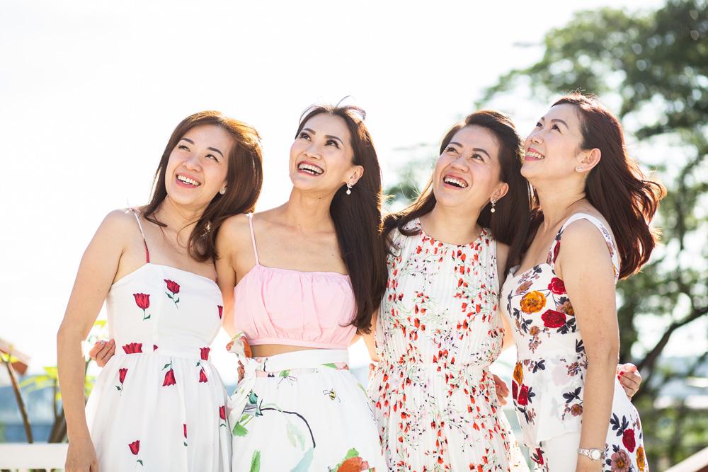 4 ladies in floral dresses looking up and posing for a picture