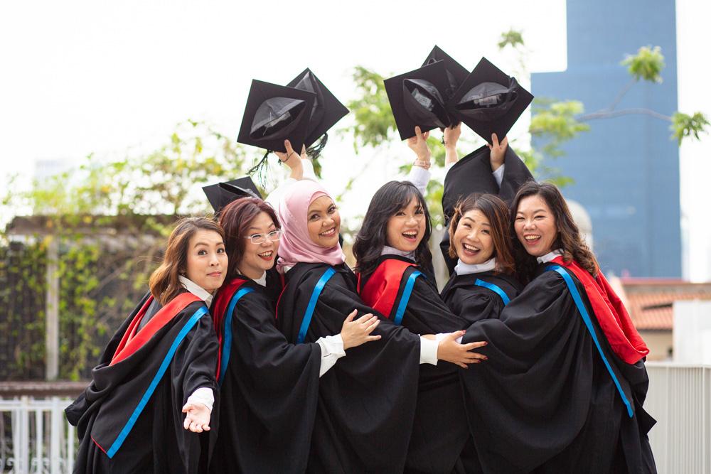 A group of ladies in their graduation gowns and posing for a picture 