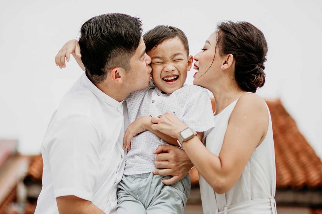 parents kissing son family photoshoot