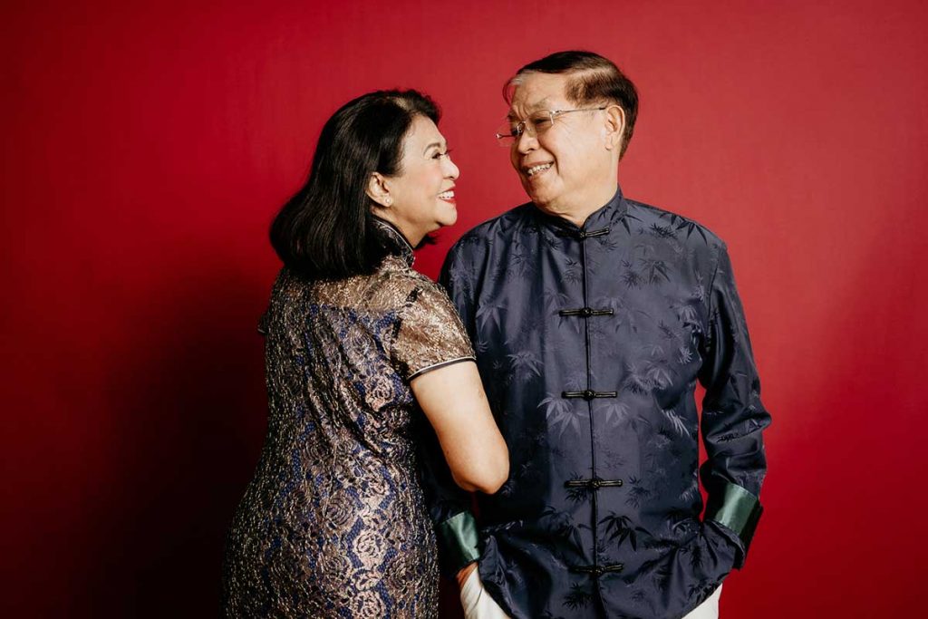 An elderly couple having a photoshoot with red backdrop