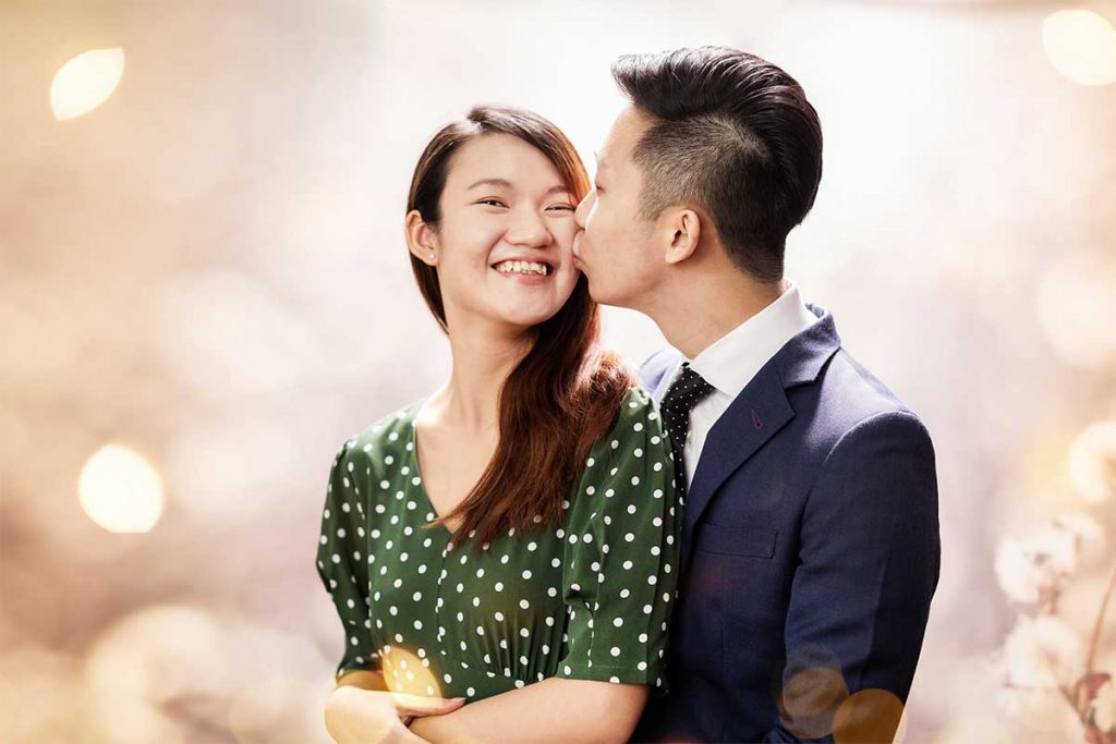 A man kissing a lady on her cheeks during a photoshoot