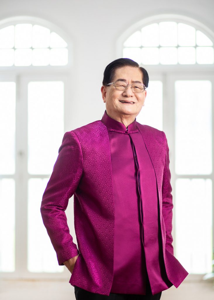 A man in a fuchsia suit smiling brightly