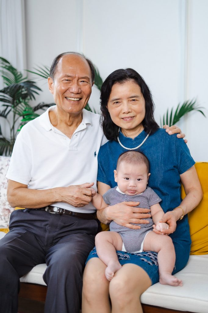 happy smiling grandparents with 100 day old baby