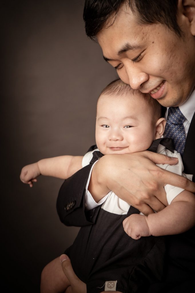 grinning 100 day old baby formal studio with father