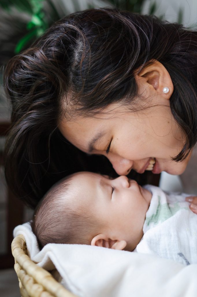 mother smiling cuddling 100 day old baby