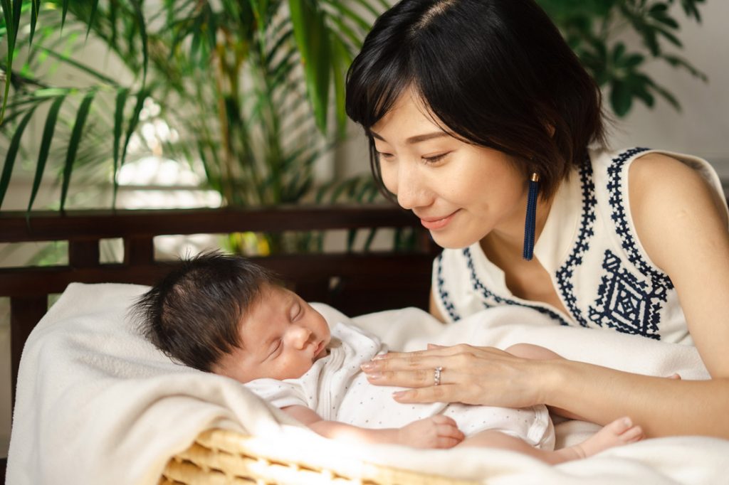 new mother smiling at sleeping newborn baby in basket oh dear studio