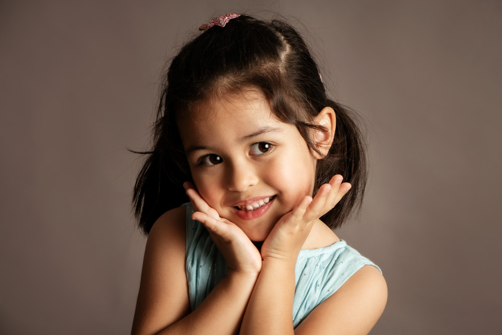 cute little girl posing in front of studio backdrop formal smiling