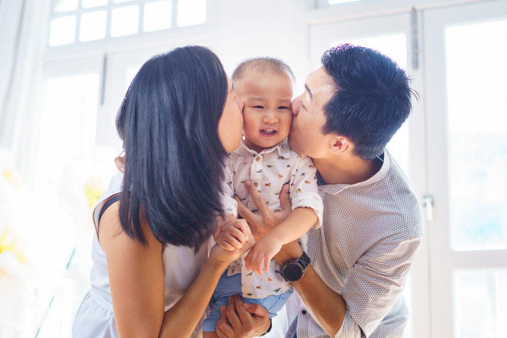 parents kissing laughing toddler photo shoot