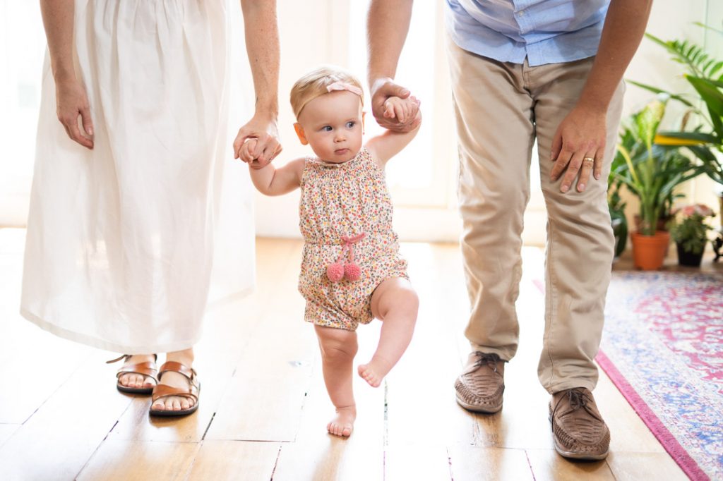 first year baby taking first step walking in photography studio