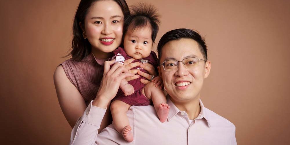 100-day-old-baby-photoshoot-with-parents parents with 100 day old baby in photo studio singapore
