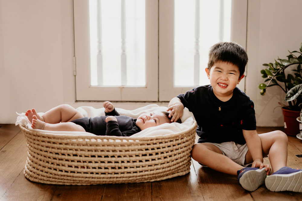 toddler and baby sister in a basket 100 day old