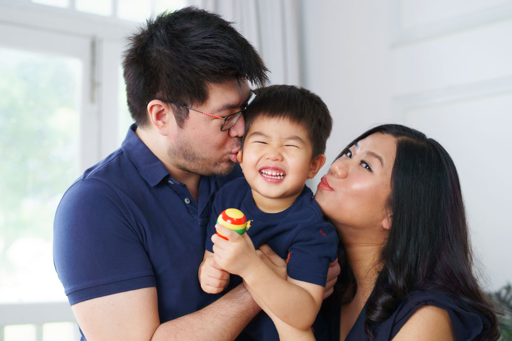 parents kissing candid laughing 3 year old toddler