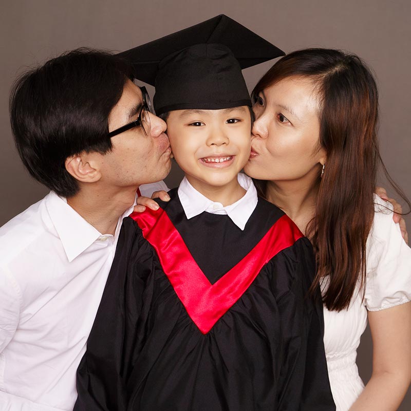 k2 graduation family photoshoot with 2 parents kissing kid