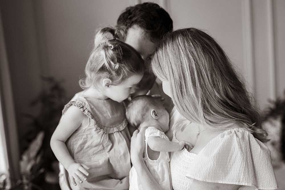 family kissing newborn photo