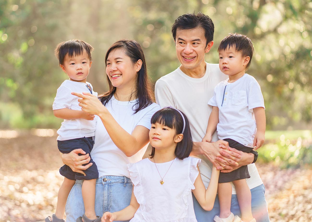 Smiling parents watching their children play in the scenic Singapore Botanic Gardens